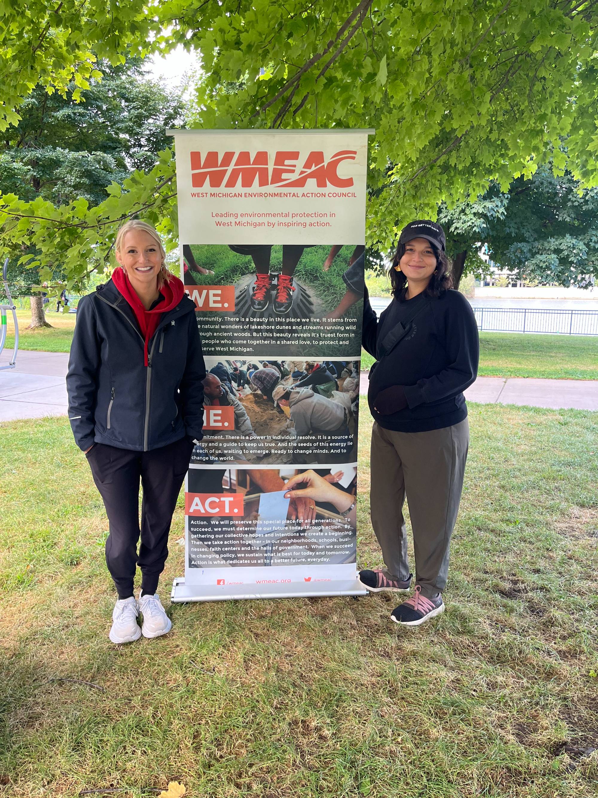 Two GLISA Team members standing in front of a banner at the Grand River Clean Up.